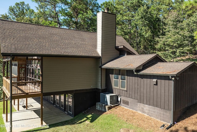 view of property exterior featuring a patio area, a lawn, a chimney, and a shingled roof