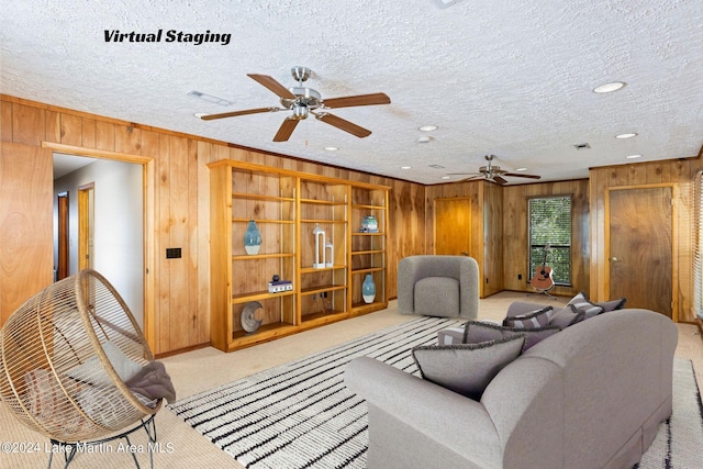 living area with wooden walls, a textured ceiling, a ceiling fan, and carpet floors