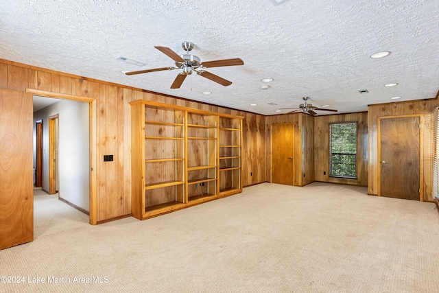 spare room featuring carpet floors, wood walls, and a ceiling fan