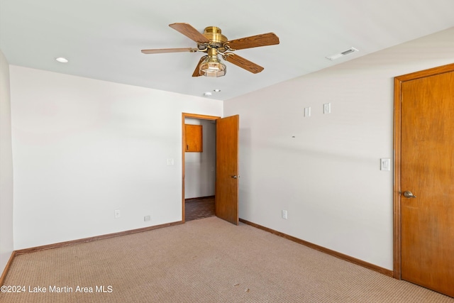 empty room with visible vents, light colored carpet, a ceiling fan, and baseboards