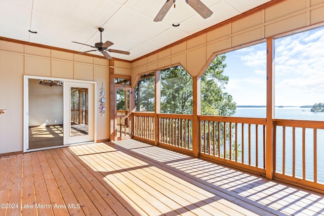 unfurnished sunroom featuring a ceiling fan and a water view