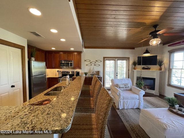 kitchen with a breakfast bar, sink, dark hardwood / wood-style floors, appliances with stainless steel finishes, and light stone counters