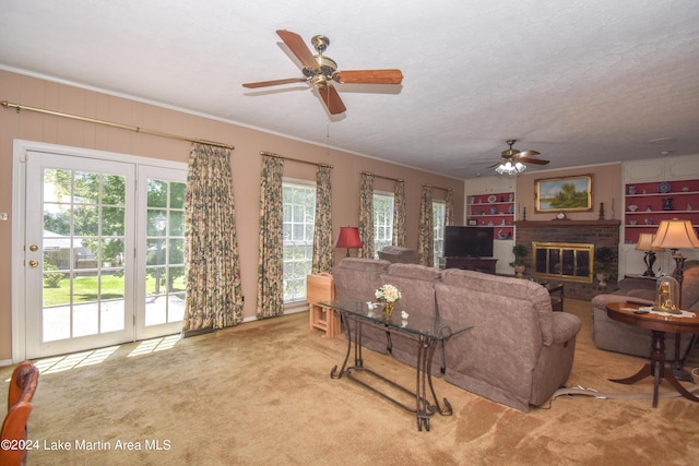 carpeted living room with a textured ceiling, ceiling fan, ornamental molding, and a fireplace