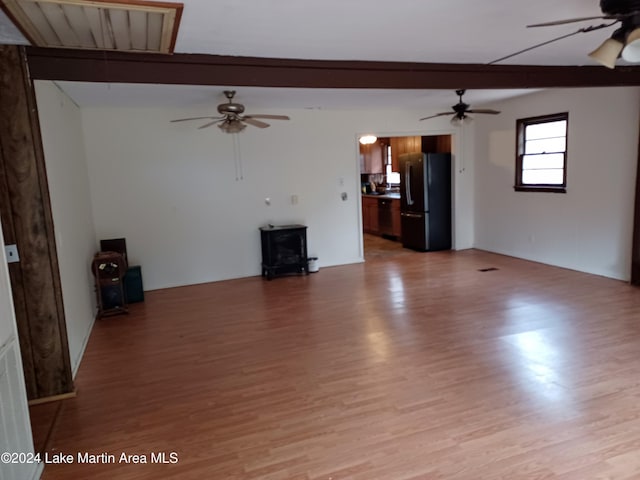 unfurnished living room featuring vaulted ceiling with beams, light hardwood / wood-style floors, and ceiling fan