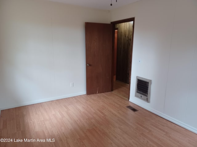 unfurnished room featuring heating unit and light hardwood / wood-style floors