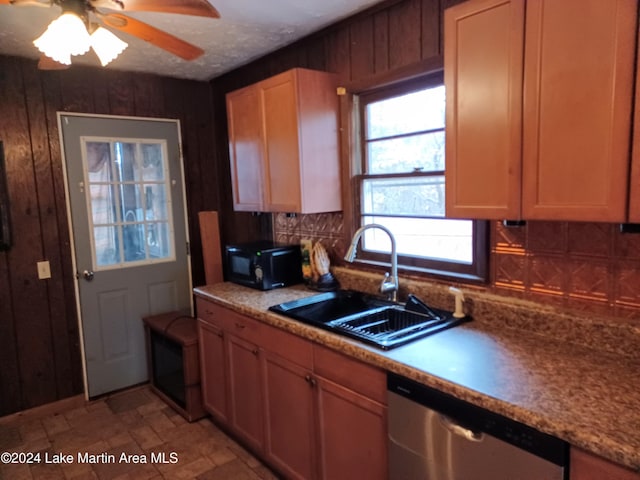 kitchen with tasteful backsplash, ceiling fan, wooden walls, sink, and dishwasher