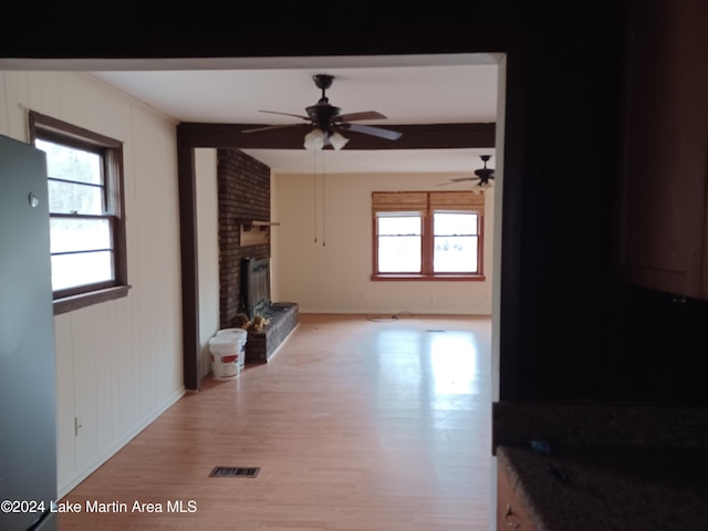 living room featuring ceiling fan, light wood-type flooring, and a brick fireplace