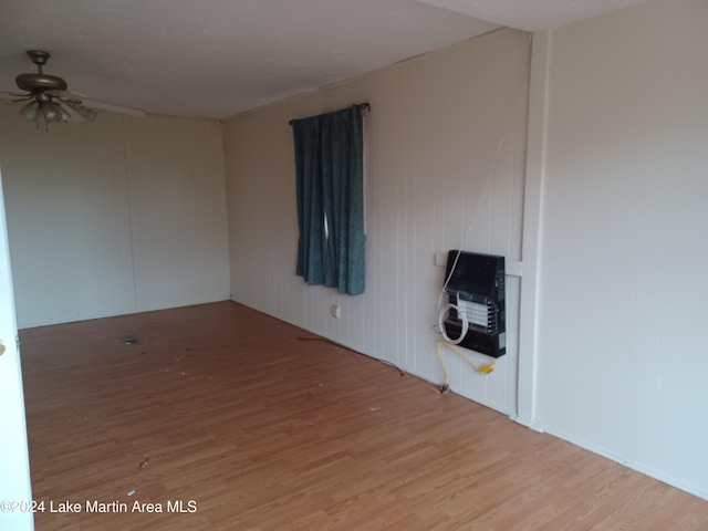 spare room with heating unit, ceiling fan, and light wood-type flooring