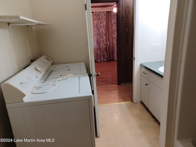 clothes washing area with washing machine and clothes dryer and light wood-type flooring