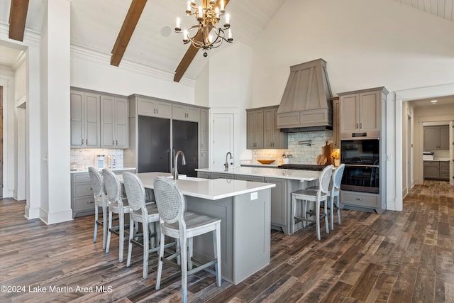 kitchen featuring pendant lighting, dark wood-type flooring, a large island with sink, high vaulted ceiling, and a breakfast bar area