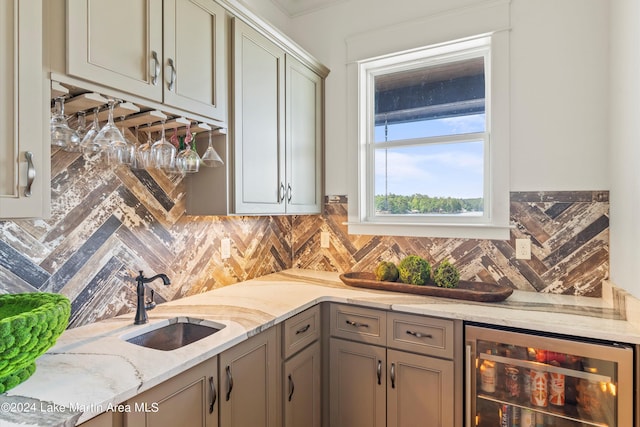 kitchen featuring decorative backsplash, light stone countertops, sink, and beverage cooler