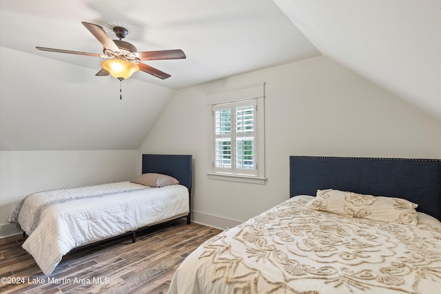 bedroom with ceiling fan, dark wood-type flooring, and vaulted ceiling