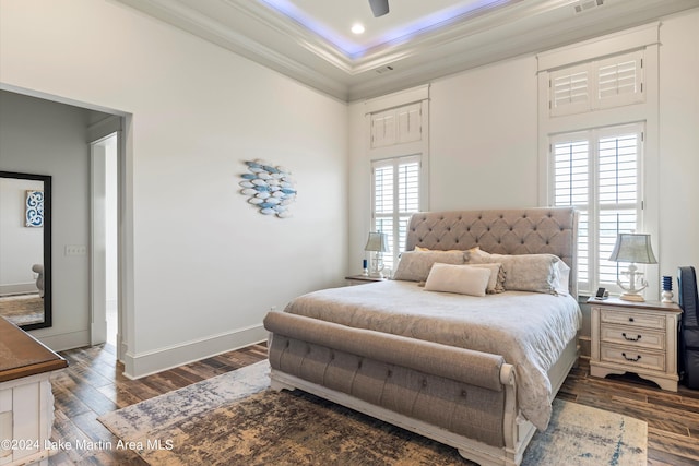 bedroom featuring dark hardwood / wood-style floors, multiple windows, ornamental molding, and ceiling fan