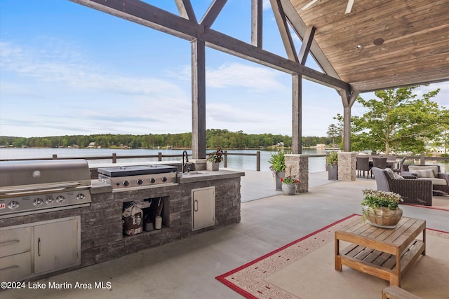 view of patio with sink, a water view, grilling area, and exterior kitchen