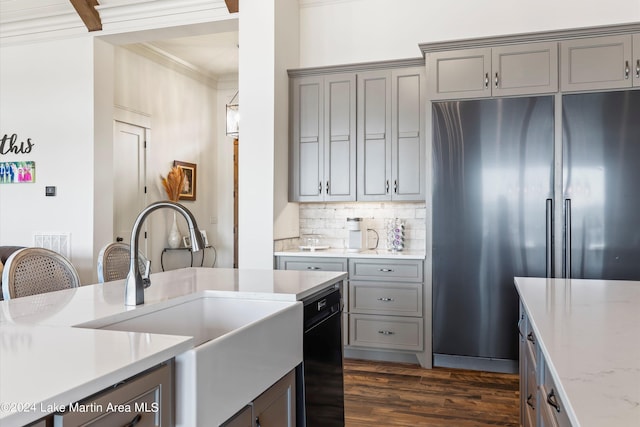 kitchen with light stone countertops, dark hardwood / wood-style flooring, crown molding, sink, and stainless steel refrigerator