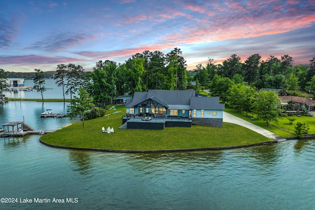 back house at dusk featuring a water view and a yard