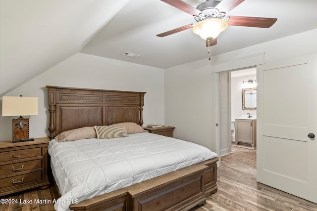 bedroom with ensuite bath, ceiling fan, sink, light hardwood / wood-style flooring, and lofted ceiling