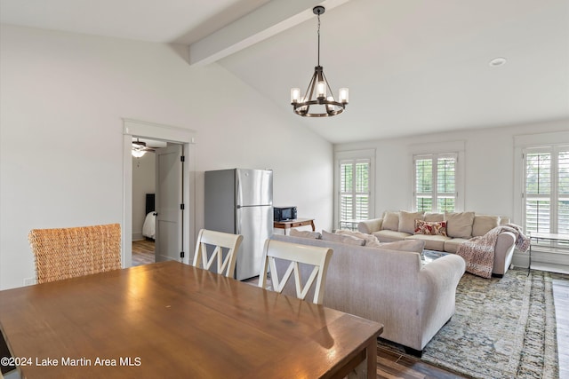 dining space with ceiling fan with notable chandelier, wood-type flooring, and vaulted ceiling with beams