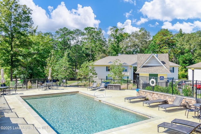 community pool with a patio area and fence