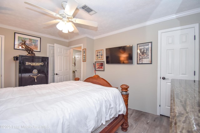 bedroom featuring crown molding, a ceiling fan, visible vents, and wood finished floors