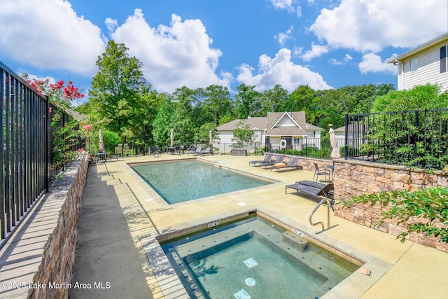 pool with a patio, a hot tub, and fence