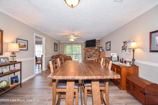 dining area featuring baseboards, a ceiling fan, wood finished floors, and a fireplace