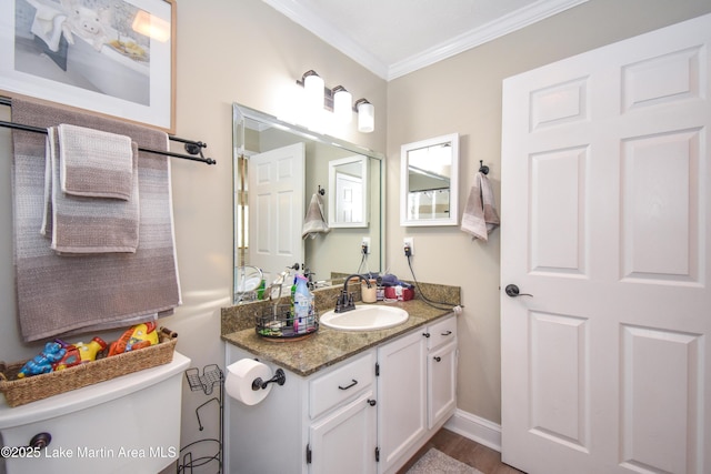 bathroom with toilet, ornamental molding, wood finished floors, and vanity