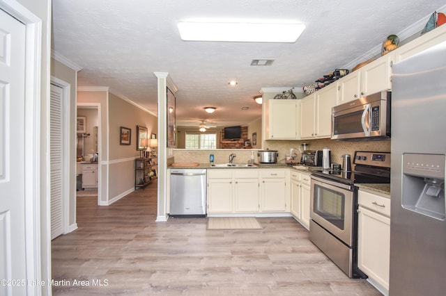 kitchen featuring ceiling fan, appliances with stainless steel finishes, tasteful backsplash, a sink, and ornamental molding