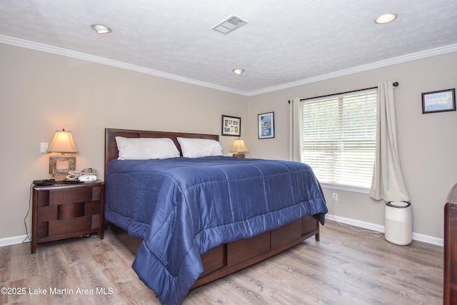bedroom with baseboards, visible vents, ornamental molding, and wood finished floors