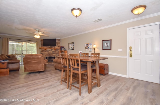 dining area with visible vents, a ceiling fan, light wood-style floors, and a fireplace
