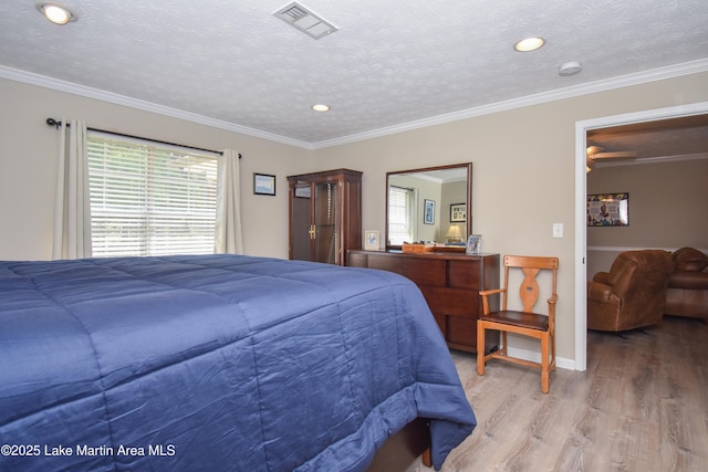bedroom with light wood-style floors, baseboards, multiple windows, and visible vents