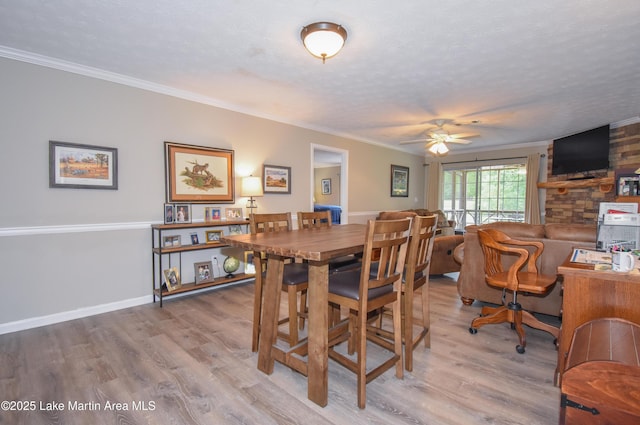 dining room with ceiling fan, a textured ceiling, crown molding, light wood-type flooring, and baseboards