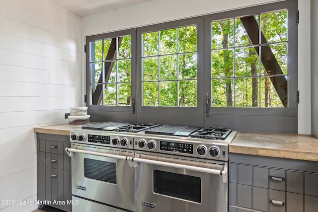 kitchen with gray cabinets, range with two ovens, and wood walls