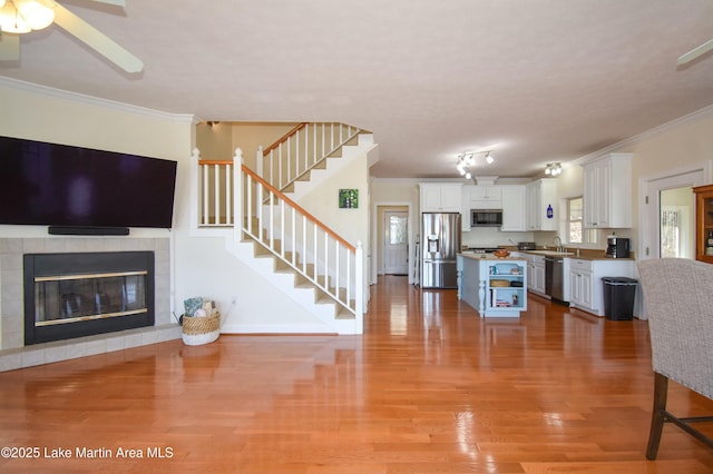 living room with light wood-style flooring, ornamental molding, and stairs