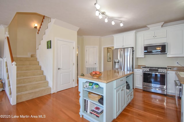 kitchen featuring white cabinets, appliances with stainless steel finishes, light wood-style flooring, and open shelves