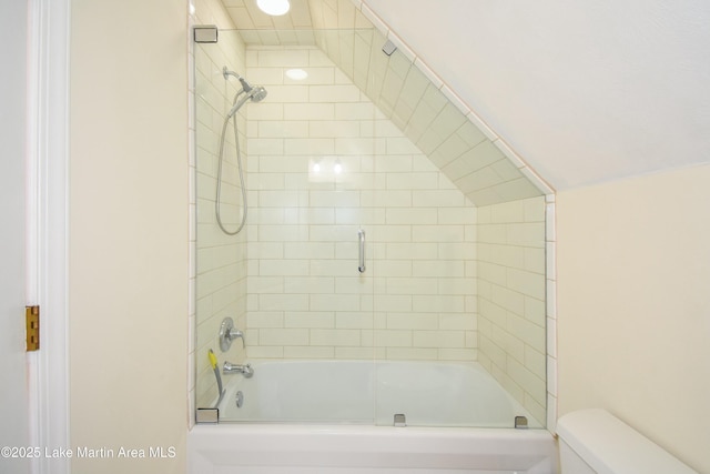 bathroom featuring toilet and bath / shower combo with glass door