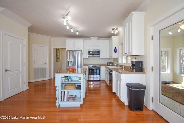 kitchen with a sink, stainless steel appliances, visible vents, and white cabinetry