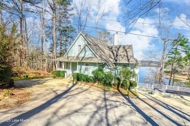 view of front facade featuring a porch, fence, driveway, and a chimney