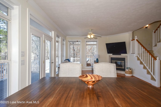 unfurnished living room featuring crown molding, stairway, a healthy amount of sunlight, and ceiling fan