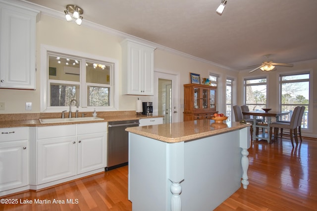 kitchen featuring light wood finished floors, a sink, white cabinets, dishwasher, and crown molding