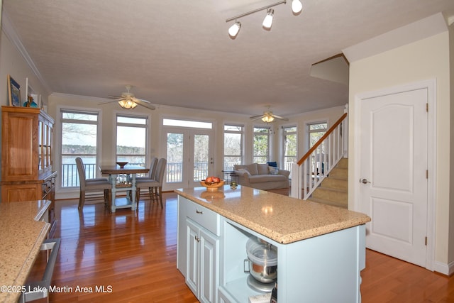 kitchen with french doors, light wood-style floors, ceiling fan, and ornamental molding