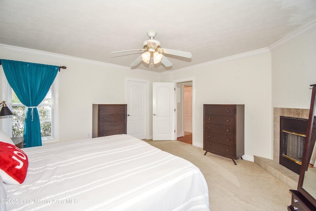 bedroom with carpet, baseboards, ceiling fan, a tiled fireplace, and crown molding