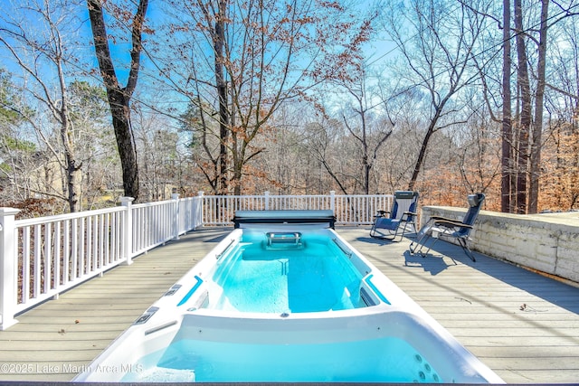 view of swimming pool featuring a wooden deck and hot tub deck surround