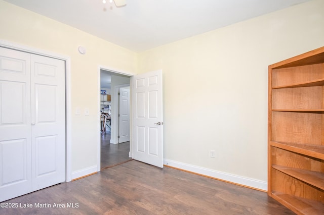 unfurnished bedroom featuring a closet, baseboards, and dark wood-style floors