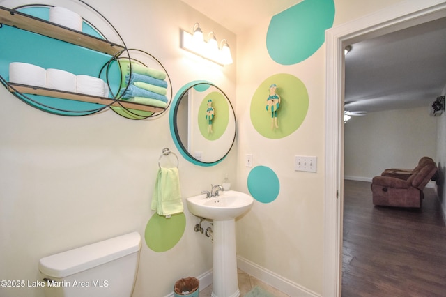 half bathroom with ceiling fan, toilet, baseboards, and wood finished floors