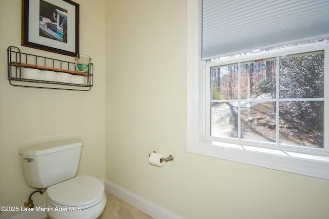 bathroom featuring a wealth of natural light, baseboards, and toilet