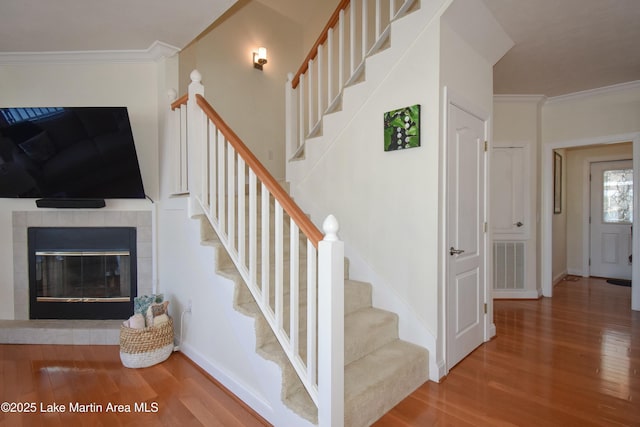 staircase featuring visible vents, wood finished floors, and crown molding