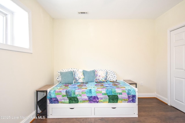 bedroom with visible vents, baseboards, and wood finished floors