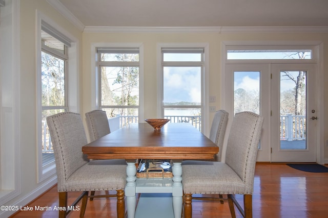 dining area with wood finished floors and ornamental molding