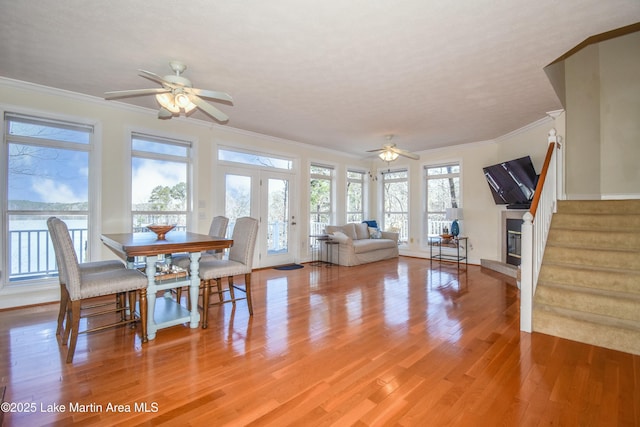 dining room with stairway, light wood-type flooring, a ceiling fan, and ornamental molding